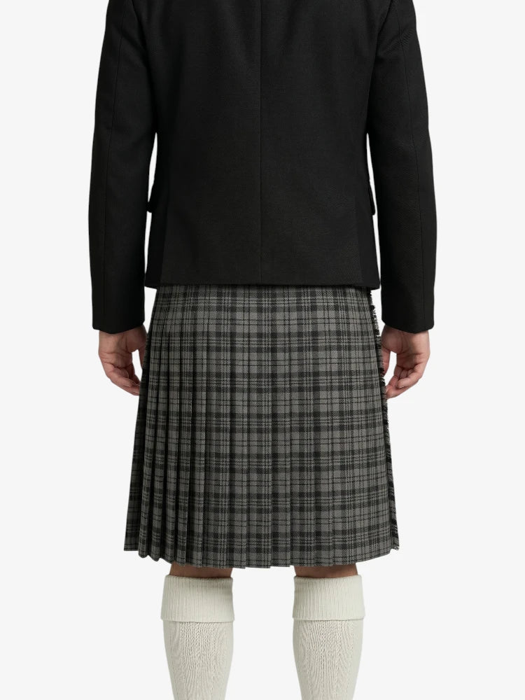 Person wearing a black jacket and plaid kilt on a white background