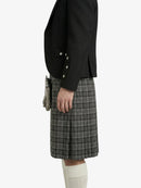 Person wearing a black jacket and plaid kilt on a white background