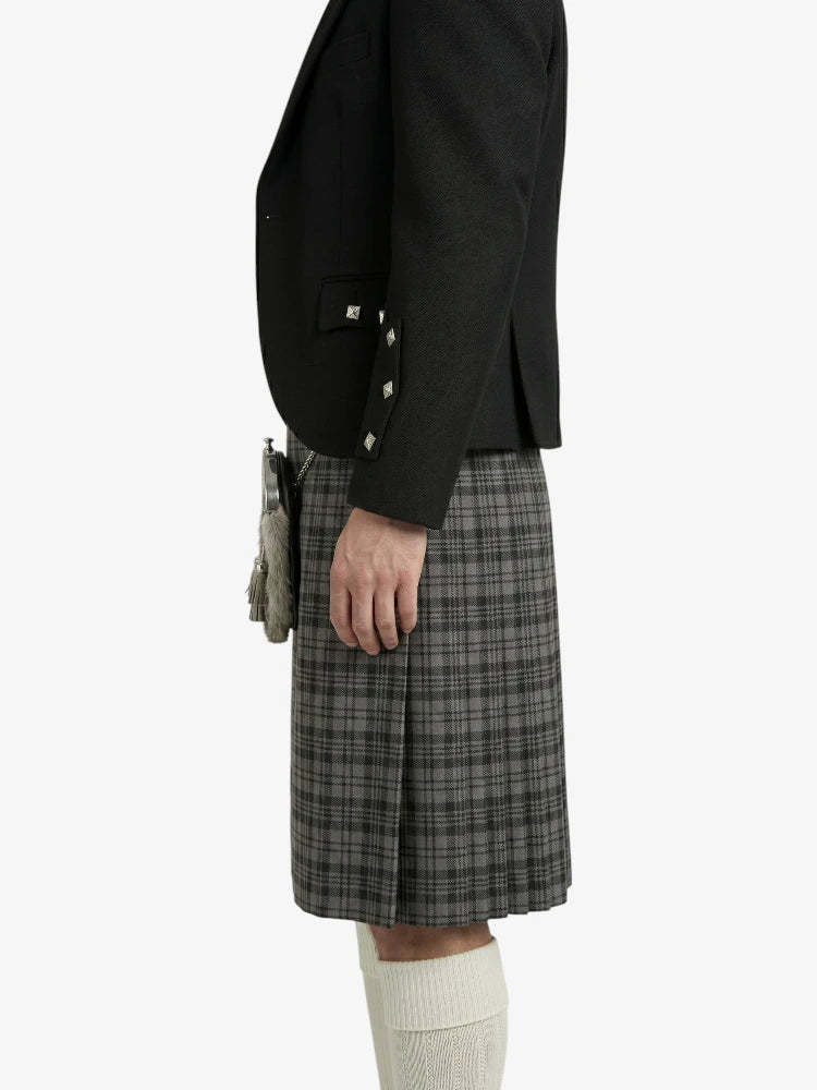 Person wearing a black jacket and plaid kilt on a white background