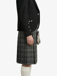Person wearing a black blazer with studded details and a plaid skirt on a white background