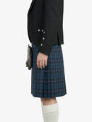 Person wearing a black blazer and blue plaid kilt on a white background