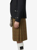 Person wearing a black jacket and plaid kilt on a white background