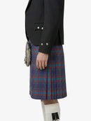 Person wearing a black blazer and blue plaid kilt on a white background