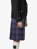 Person wearing a black jacket and blue plaid kilt on a white background