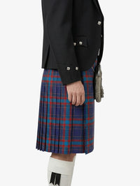 Person wearing a black jacket and blue plaid kilt on a white background