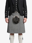 Person wearing a black jacket with white buttons, a kilt, and white knee-high socks on a white background