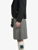 Person wearing a black jacket and gray checkered kilt on a white background