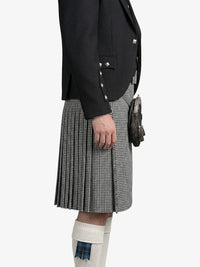 Person wearing a black blazer and houndstooth pattern kilt on a white background
