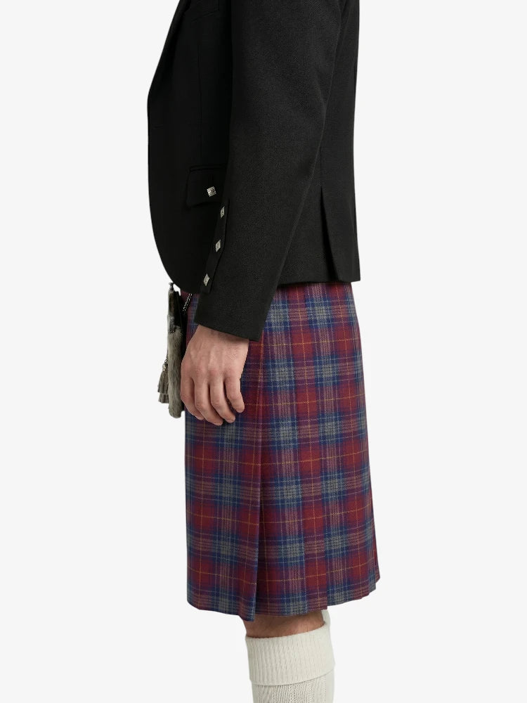 Person wearing a black jacket and red plaid kilt on a white background