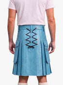 A person shown from the back wearing a light blue pleated kilt with black lace-up detailing down the center and side flap pockets, paired with a pale pink T-shirt and light socks against a plain light background.