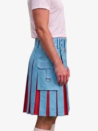 A person wearing a light blue pleated kilt with vertical red stripes and silver metal hardware, paired with a white t-shirt, shown from the side against a plain light gray background.