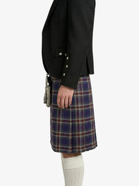 Person wearing a black blazer and plaid kilt on a white background