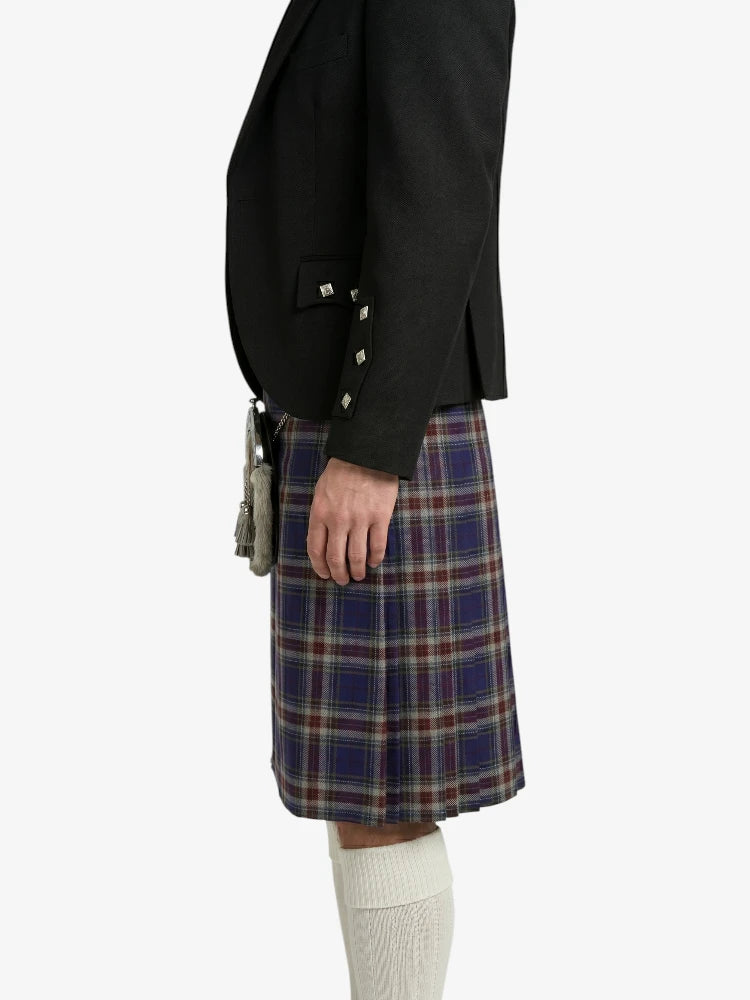 Person wearing a black blazer and plaid kilt on a white background