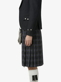 Person wearing a black blazer and plaid kilt on a white background