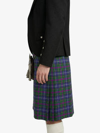 Person wearing a black blazer and a green and purple plaid kilt on a white background