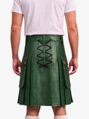 A person shown from the back wearing a dark green faux-leather kilt with a central lace-up closure and side flap pockets, paired with a light pink t-shirt and white socks against a plain white background.