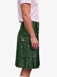 A side view of a person wearing a dark green faux-leather kilt with pleated detailing, side pockets, and silver snap buttons, paired with a light pink t-shirt against a plain white background.