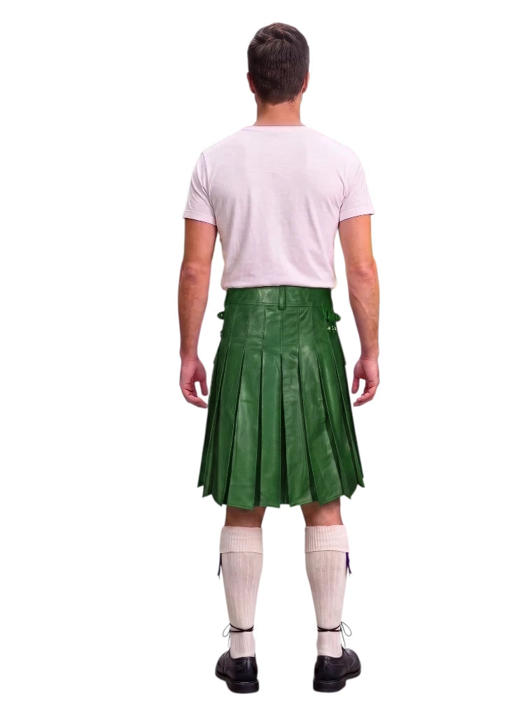 A man shown from the back wearing a green pleated kilt, a light pink t-shirt, white knee-high socks, and black shoes, against a plain white background.