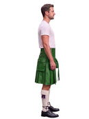 A man shown in profile wearing a green leather kilt, a white t-shirt, white knee-high socks, and black leather shoes, against a plain white background.