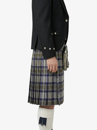 Person wearing a black jacket and plaid kilt on a white background
