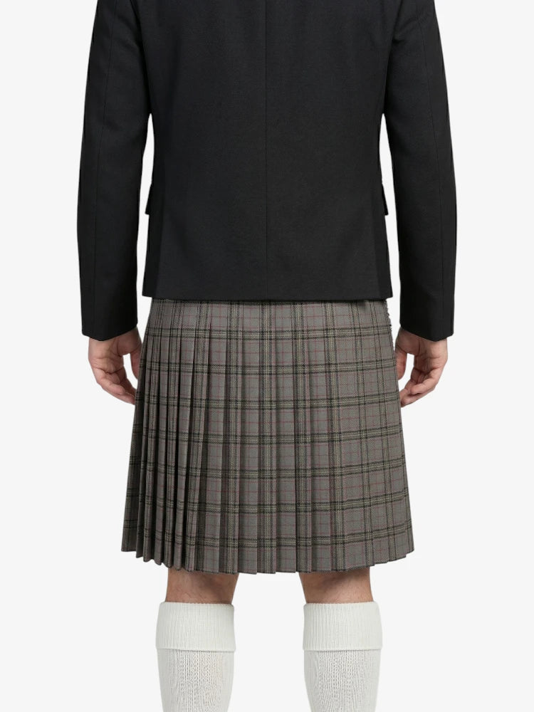 Person wearing a black jacket and plaid kilt on a white background