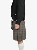 Person wearing a black blazer and plaid kilt on a white background