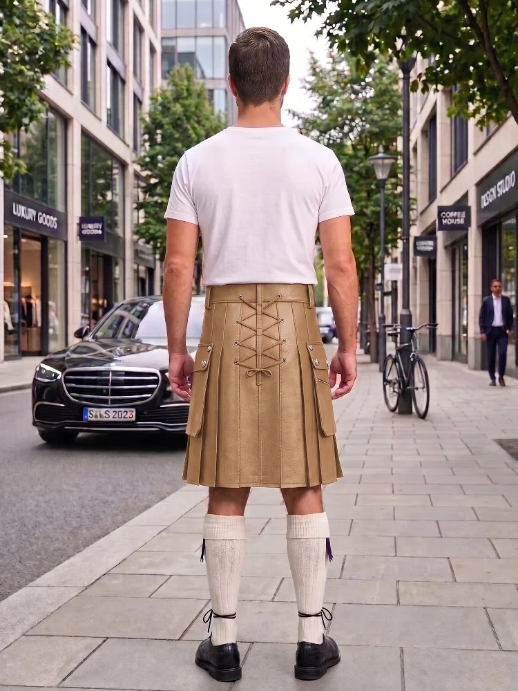 A man viewed from behind wearing a beige pleated kilt with lace-up back detailing, a white t-shirt, white knee-high socks, and black shoes, standing on a city sidewalk.