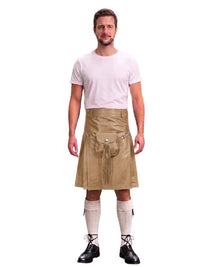 A man modeling a tan faux-leather kilt with a front flap pocket and drawstring, styled with a white t-shirt, cream knee-high socks, and black lace-up boots against a white background.