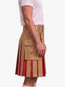 A side view of a person wearing a tan pleated kilt with red vertical pleated inserts and a matching tan belt, paired with a white t-shirt against a light gray background.