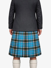 Person wearing a gray blazer and blue plaid kilt on a white background