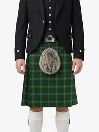Person wearing a green plaid kilt with a black jacket and white socks on a white background
