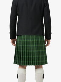 Person wearing a black jacket and green plaid kilt on a white background