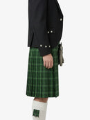 Person wearing a black jacket and green plaid kilt on a white background