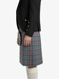 Person wearing a black jacket and blue plaid kilt on a white background