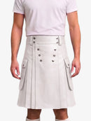 A person wearing a light gray pleated faux-leather kilt with double-breasted silver buttons and side flap pockets, paired with a pale pink t-shirt against a light gray background.