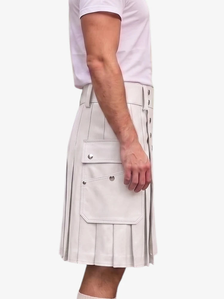 A person wearing a light beige pleated kilt with side pockets and decorative metal rivets, paired with a pale pink t-shirt, shown from the side against a plain white background.