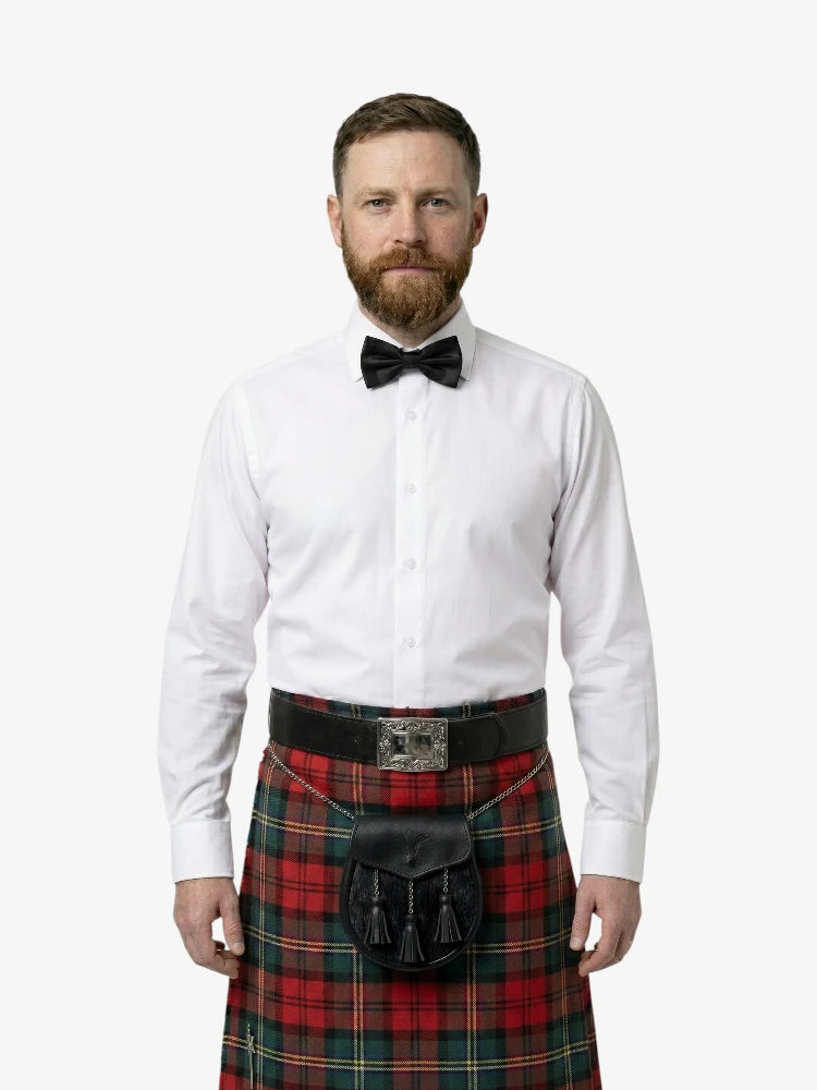 Man wearing a white shirt, black bow tie, and red plaid kilt on a white background