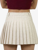 Beige pleated skirt worn by a person on a white background