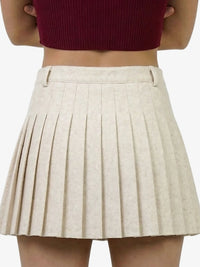 Beige pleated skirt worn by a person on a white background