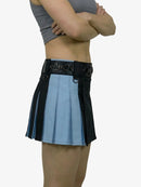 Person wearing a unique skirt design with black and blue pleats on a white background