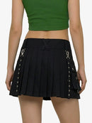 Black pleated skirt with silver buckles worn by a person on a white background