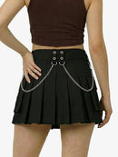 Black pleated skirt with chain details worn by a person on a white background