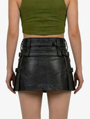 Person wearing a green crop top and black leather skirt with belt details on a white background
