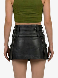 Person wearing a green crop top and black leather skirt with belt details on a white background