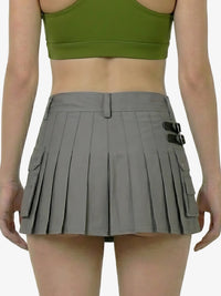 Person wearing a green sports bra and gray pleated skirt on a white background