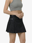 Person wearing a black pleated skirt and gray crop top on a white background