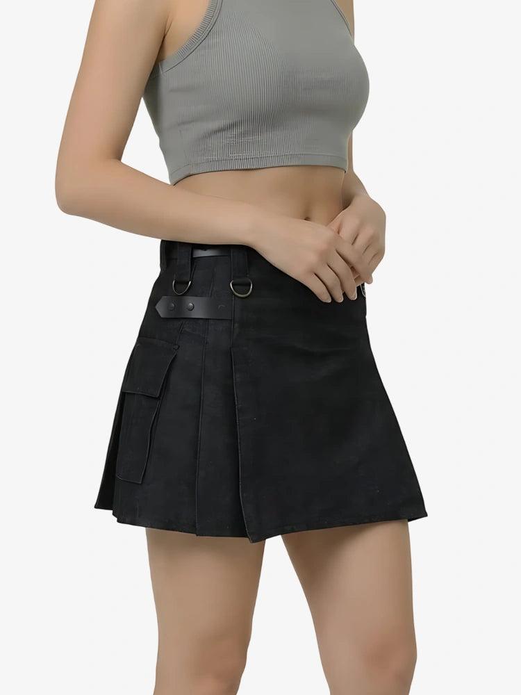 Person wearing a black pleated skirt and gray crop top on a white background