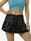 Person wearing a black skirt with silver buckles and rings on a plain background