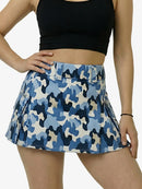 Person wearing a black crop top and blue camouflage skirt on a white background