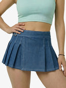 Person wearing a blue pleated skirt and light green crop top on a white background